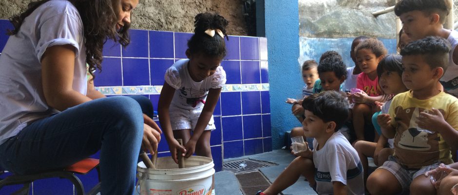 Sometimes a bucket full of soil is the most interesting thing: Elisângela (Horta Inteligente) planting seeds with kids from the Tia Dora daycare