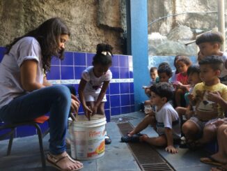 Sometimes a bucket full of soil is the most interesting thing: Elisângela (Horta Inteligente) planting seeds with kids from the Tia Dora daycare