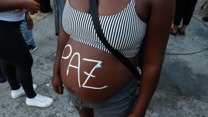 Pregnant protester paints "Peace" on her belly during march. Photo: Alexandre Cerqueira