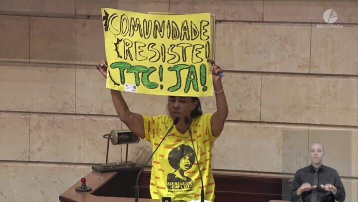Jurema da Silva, resident of the Shangri-lá Cooperative, defends the inclusion of the CLT in the Master Plan holding a sign "Community Resists! CLT! Now!"