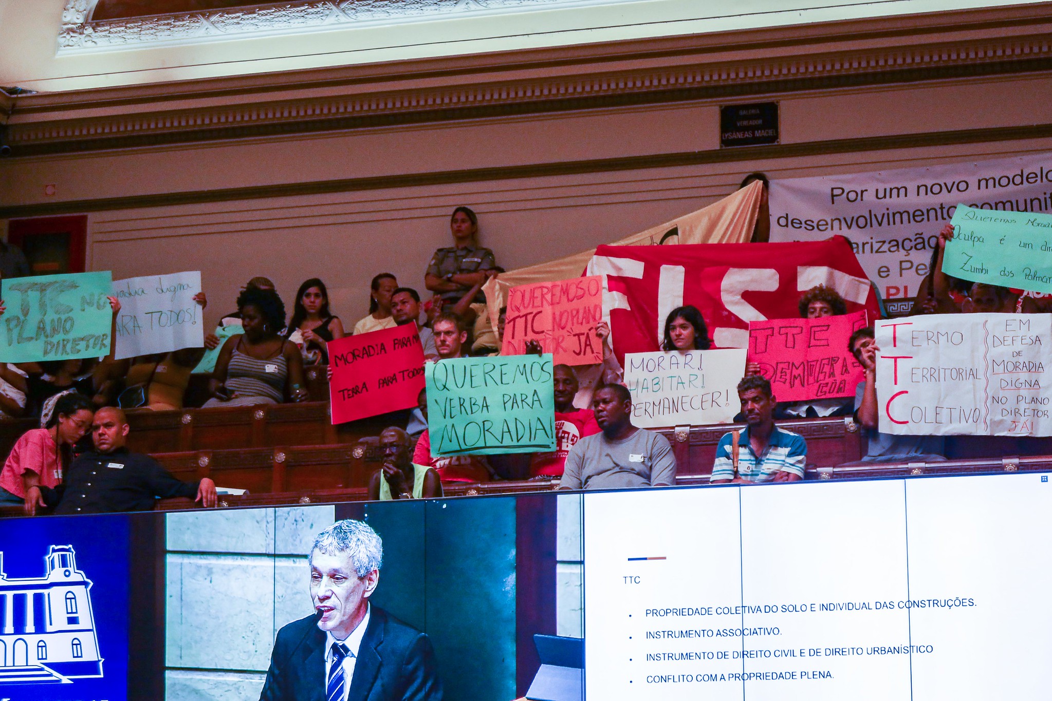 Members of the public demonstrate support for the Community Land Trust (CLT) remaining in the Rio de Janeiro Master Plan with signs and banners at the public hearing on April 5. 