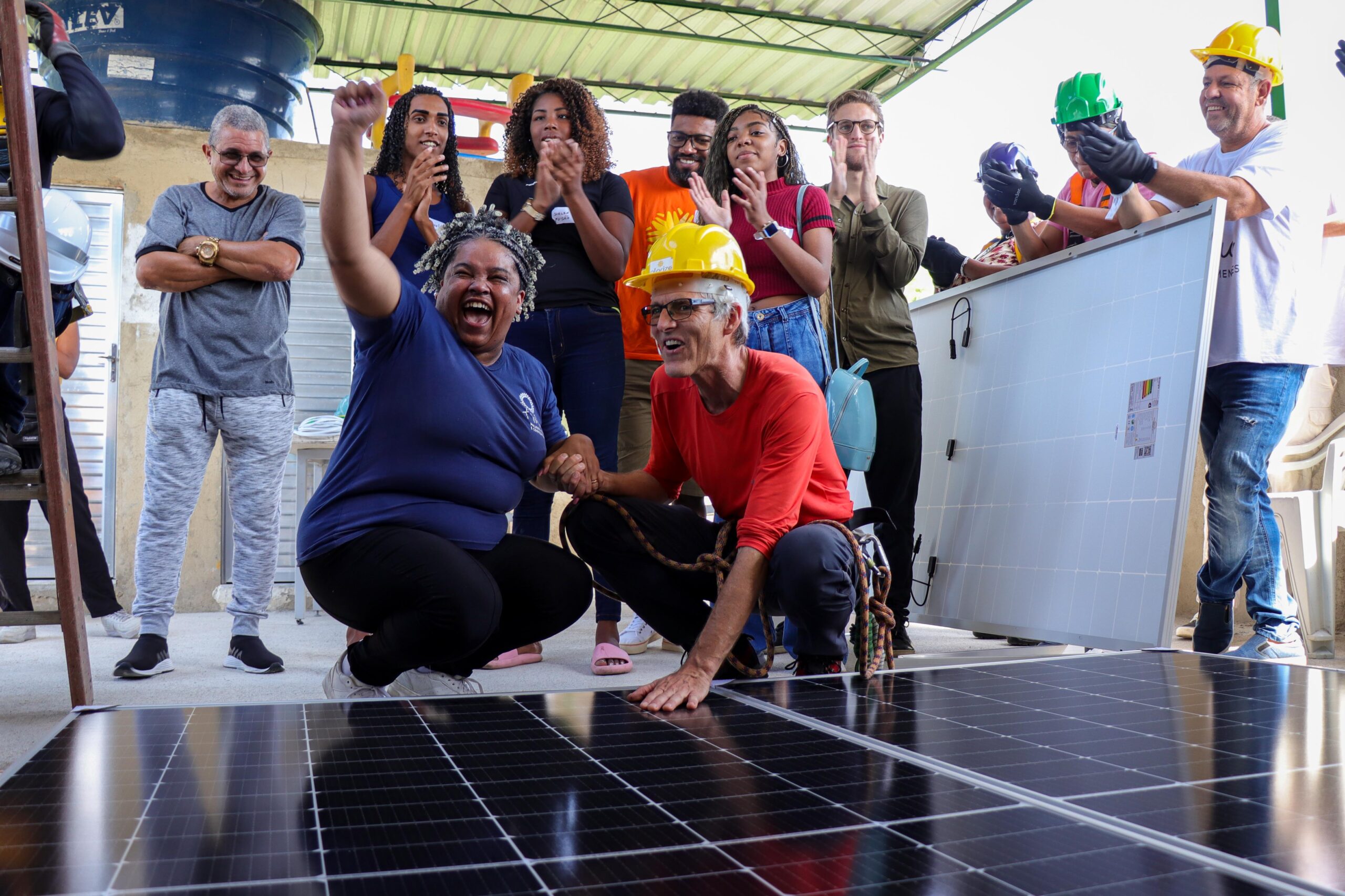 Nill Santos, President of AMAC, celebrates the arrival of the photovoltaic panels at the association’s headquarters alongside Hans Rauschmayer from Solarize. Photo: Alexandre Cerqueira/RioOnWatch