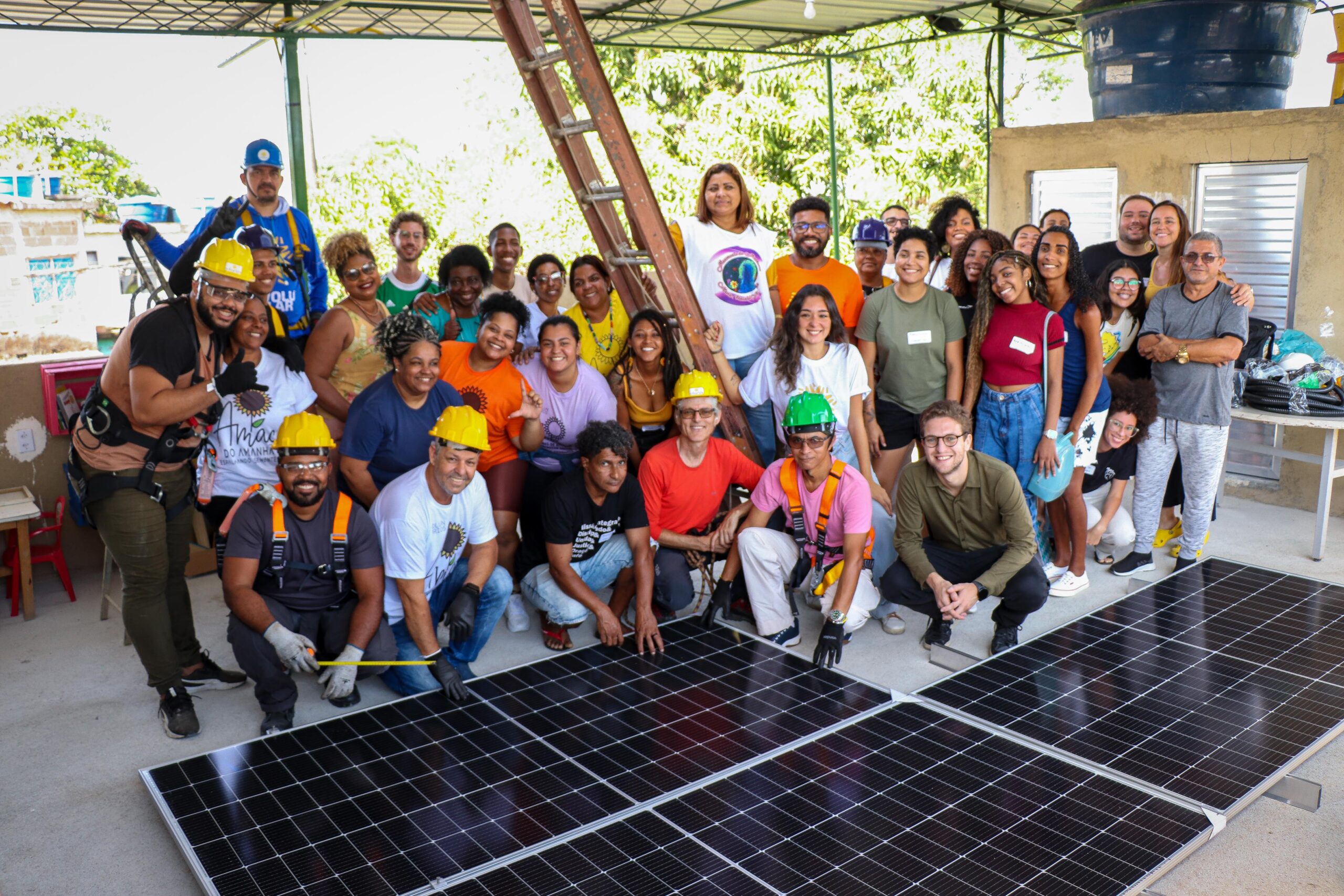 Participants of the Sustainable Favela Network's Mini-course for Solar Energy Ambassadors gather around the panels to be installed. Photo: Alexandre Cerqueira