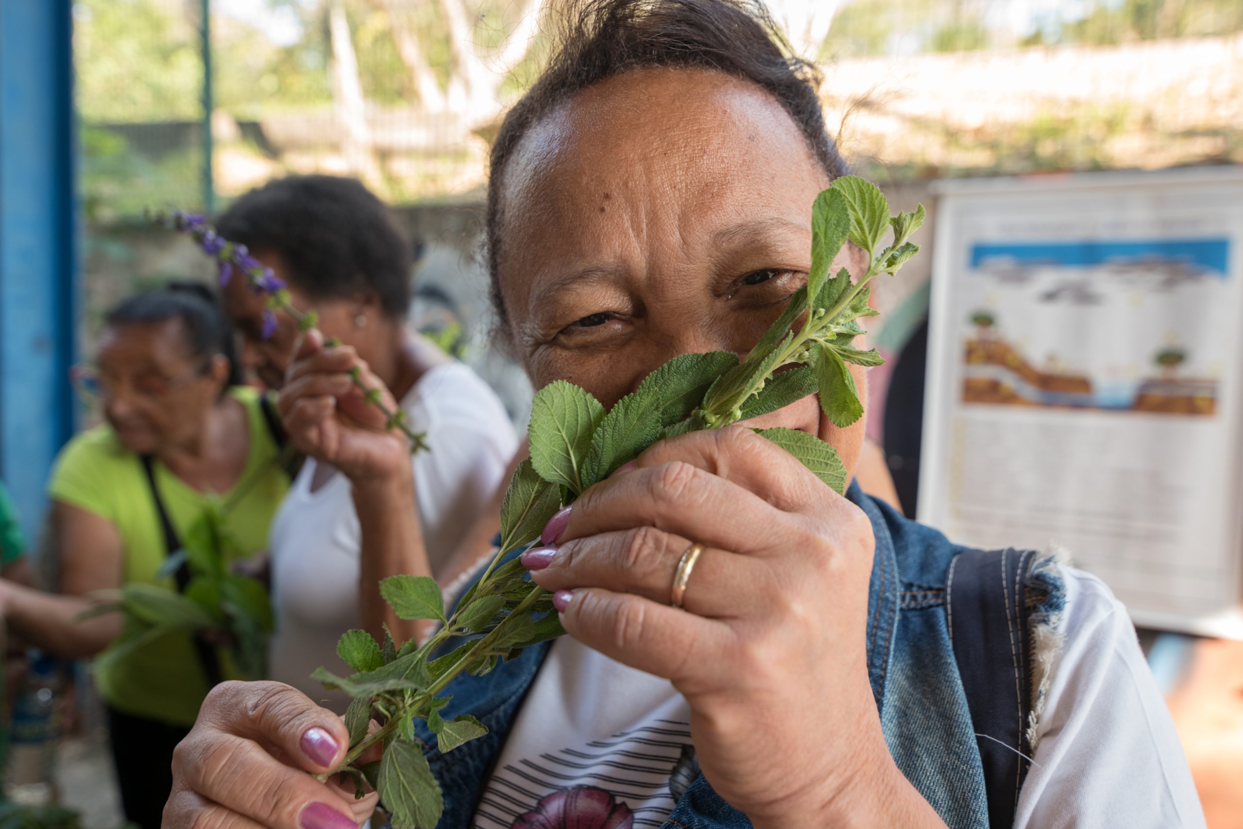 Participant of the event SFN's Wisdoms and Flavors from the Heart smells an herb at the Salgueiro Herb Growers booth during Filmambiente. Photo Barbara Dias/CatComm