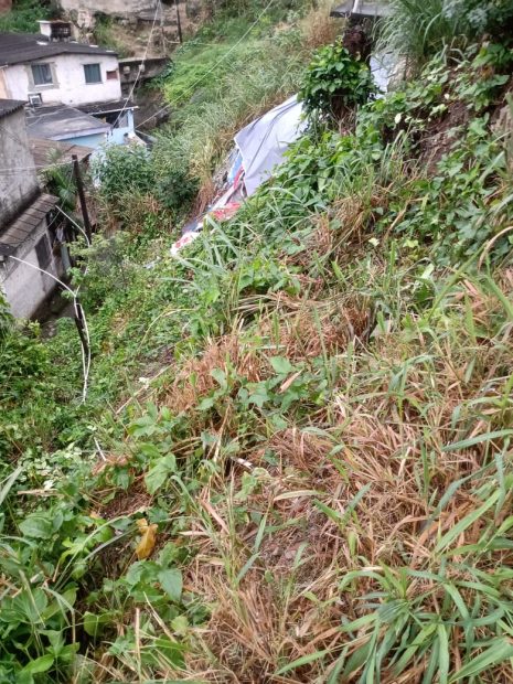 Prates described how the ravine at the base of a house collapsed, hit the house below, and blocked the path for months. He pointed out that the white house below has a mark on the wall indicating how high the mud reached during the last landslide. Photo: Lucas Prates/18 Family Social Project