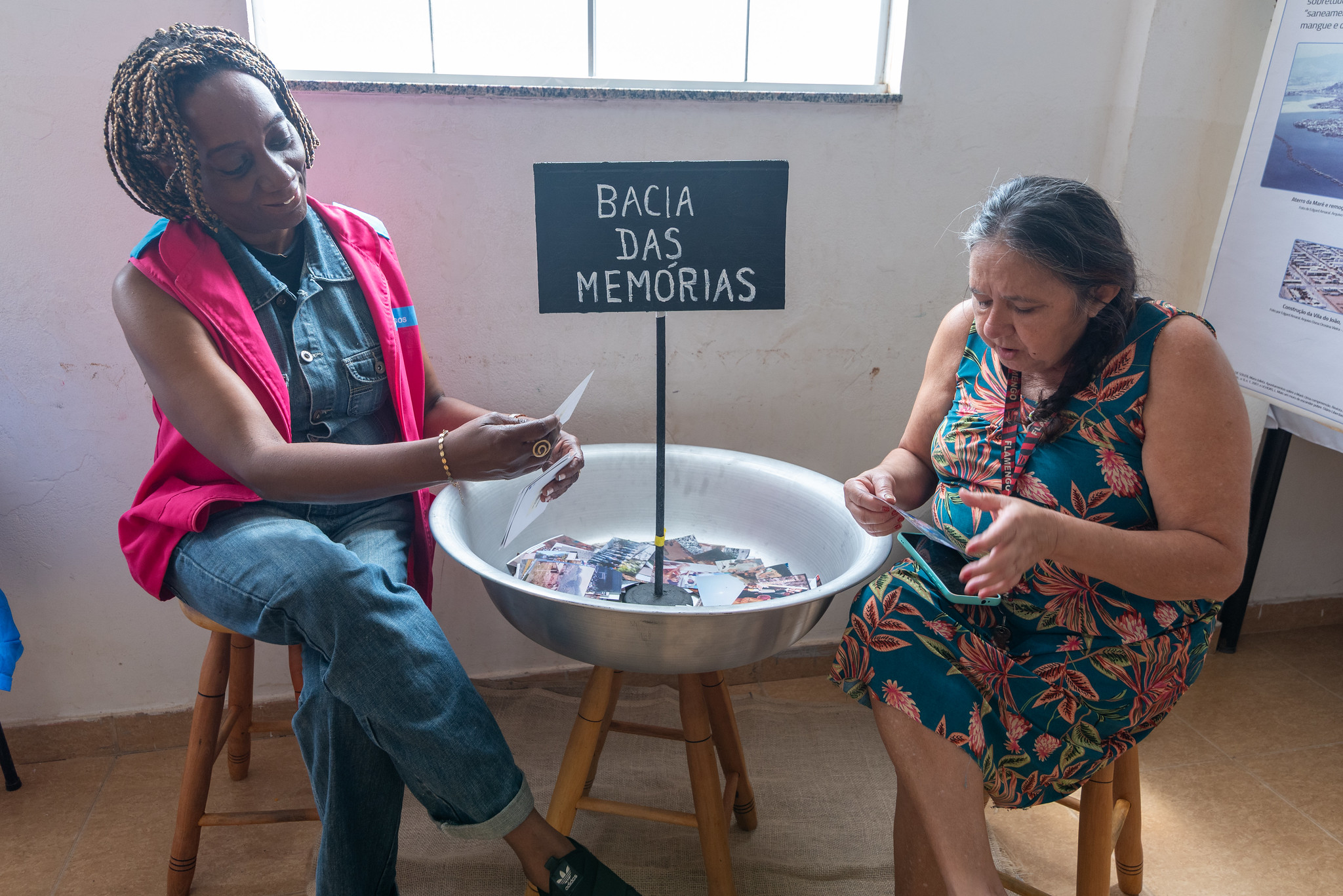 Os moradores interagem com a bacia das memórias, procurando fotos históricas das favelas apresentadas na exposição. Foto: Bárbara Dias