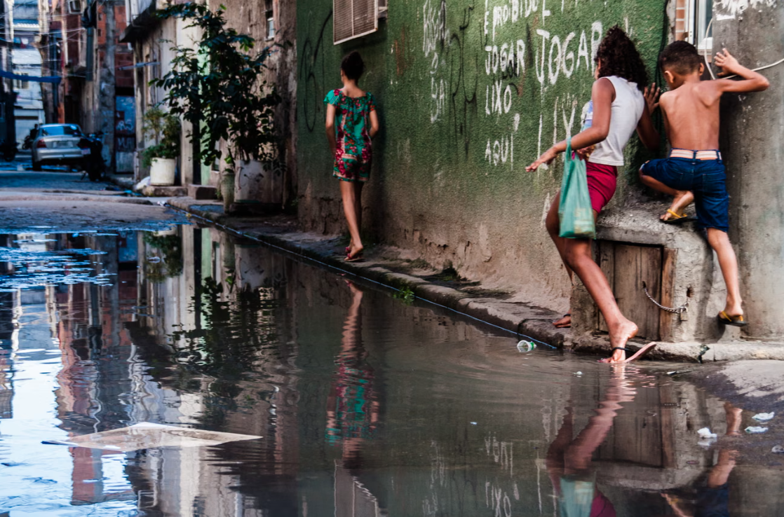 Children in Maré, one of Rio’s many favelas, try to avoid the sewage-laden flood water on a street. The writing on the wall says: ‘It’s forbidden to leave rubbish here.’ Maré expanded quickly in the 1940s until the city authorities moved part of its residents to Antares, 40 miles away. Photograph: AF Rodrigues/Guardian Children in Maré, one of Rio’s many favelas, try to avoid the sewage-laden flood water on a street. The writing on the wall says: ‘It’s forbidden to leave rubbish here.’ Maré expanded quickly in the 1940s until the city authorities moved part of its residents to Antares, 40 miles away. Photograph: AF Rodrigues/Guardian