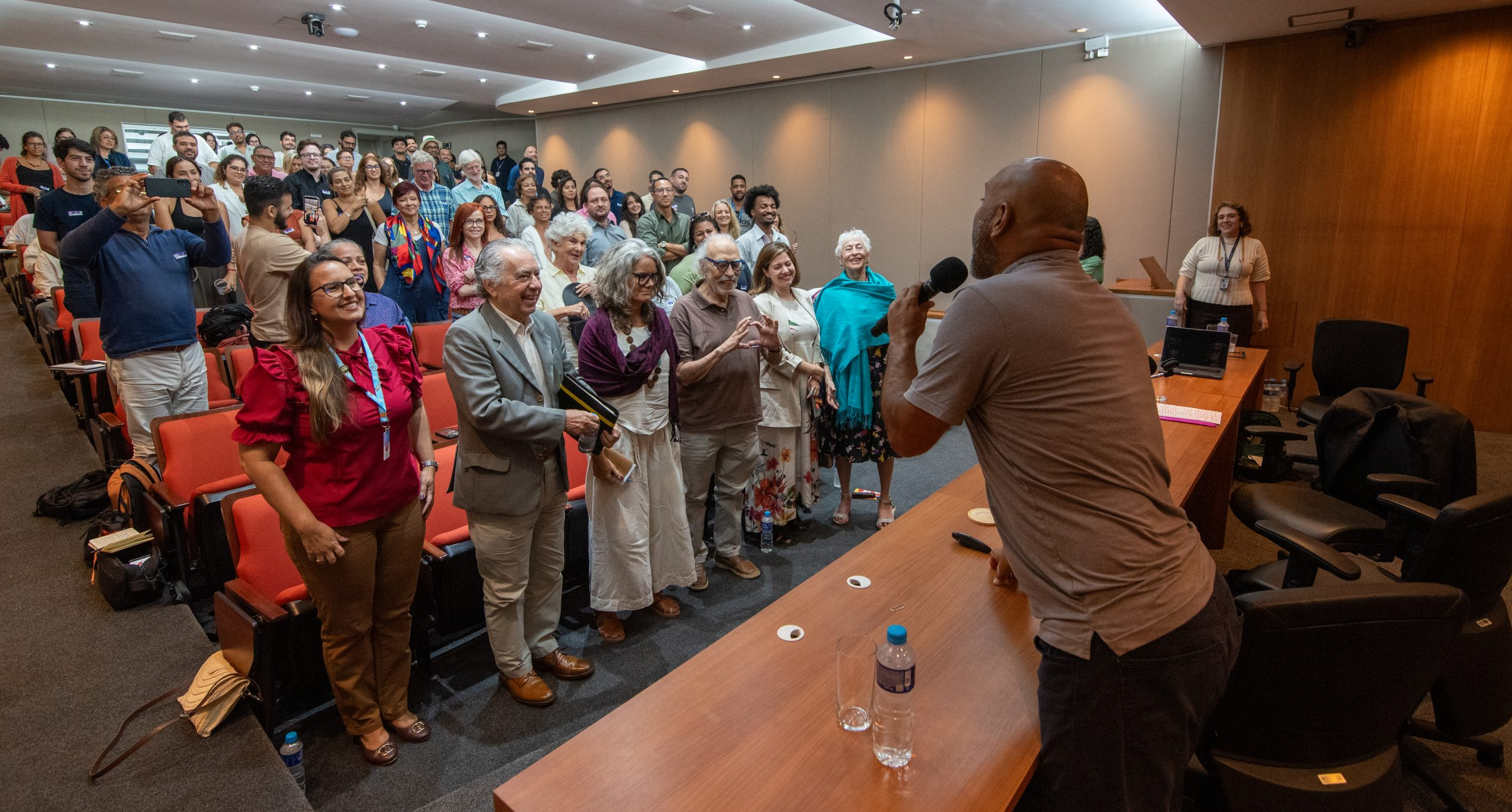 Audience members in the auditorium participate in an activity led by a speaker, chanting ‘I believe in Rio!’ Photo: Bárbara Dias Audience members in the auditorium participate in an activity led by a speaker, chanting ‘I believe in Rio!’ Photo: Bárbara Dias