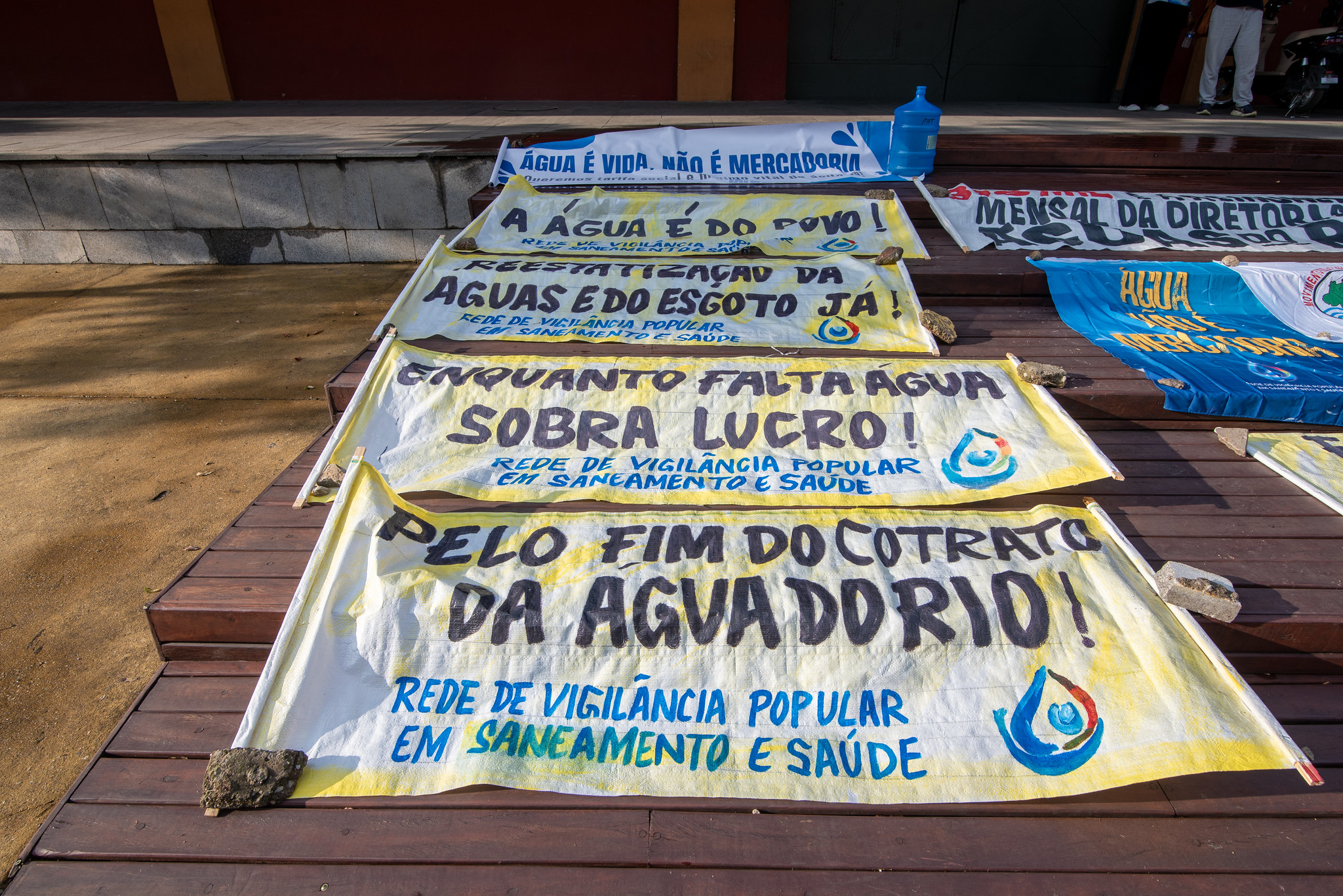 Banners on the ground with messages such as “End Águas do Rio’s contract,” “While water is scarce, profits abound!” and “Re-nationalize water and sewage.” Photo: Bárbara Dias Banners on the ground with messages such as “End Águas do Rio’s contract,” “While water is scarce, profits abound!” and “Re-nationalize water and sewage.” Photo: Bárbara Dias