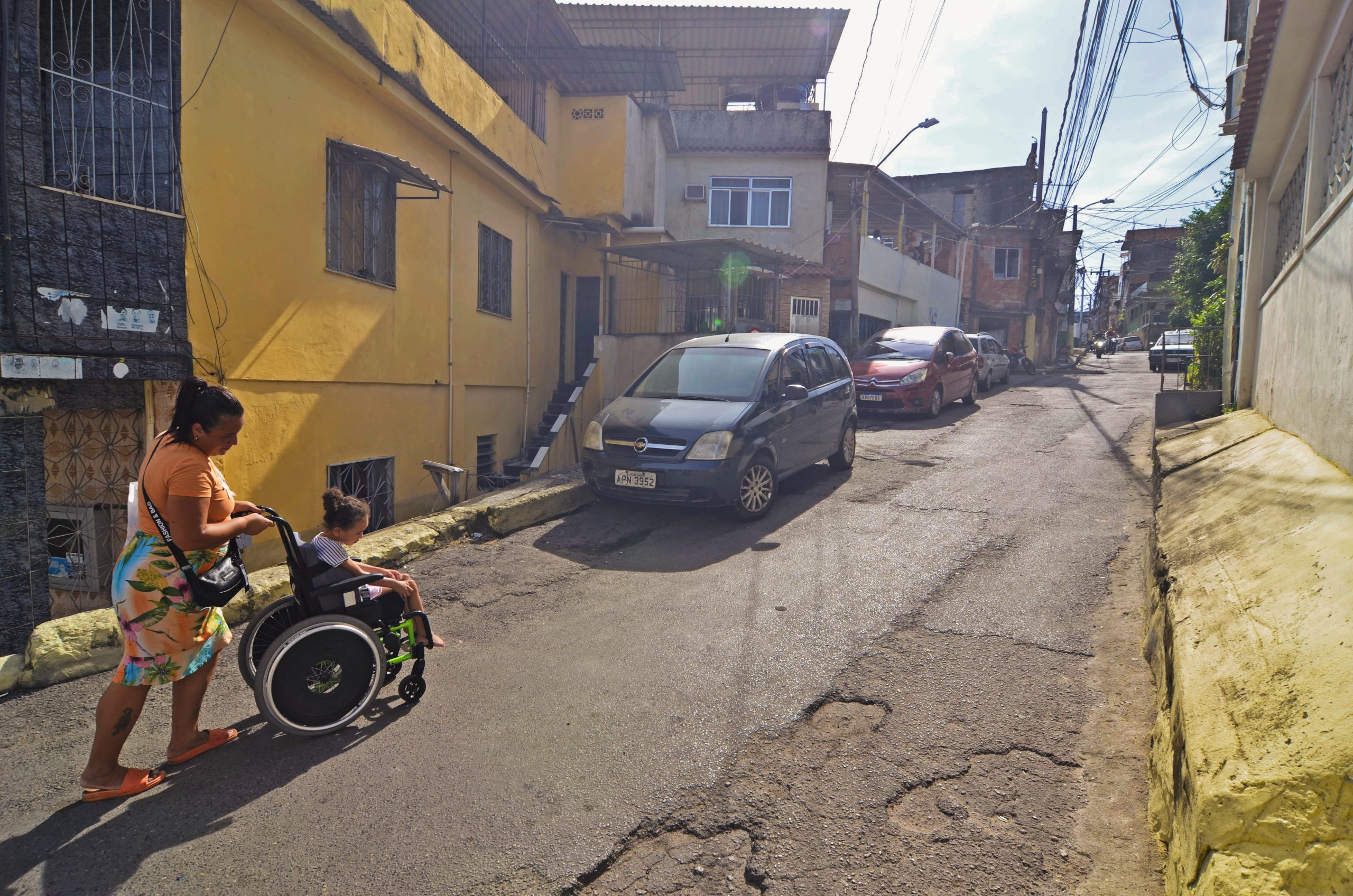 In Morro do Timbau, a paved road designed for cars rather than pedestrians exposes Eloá and her mother to potholes and motorcycle and car traffic. Photo: Ramon Vellasco In Morro do Timbau, a paved road designed for cars rather than pedestrians exposes Eloá and her mother to potholes and motorcycle and car traffic. Photo: Ramon Vellasco